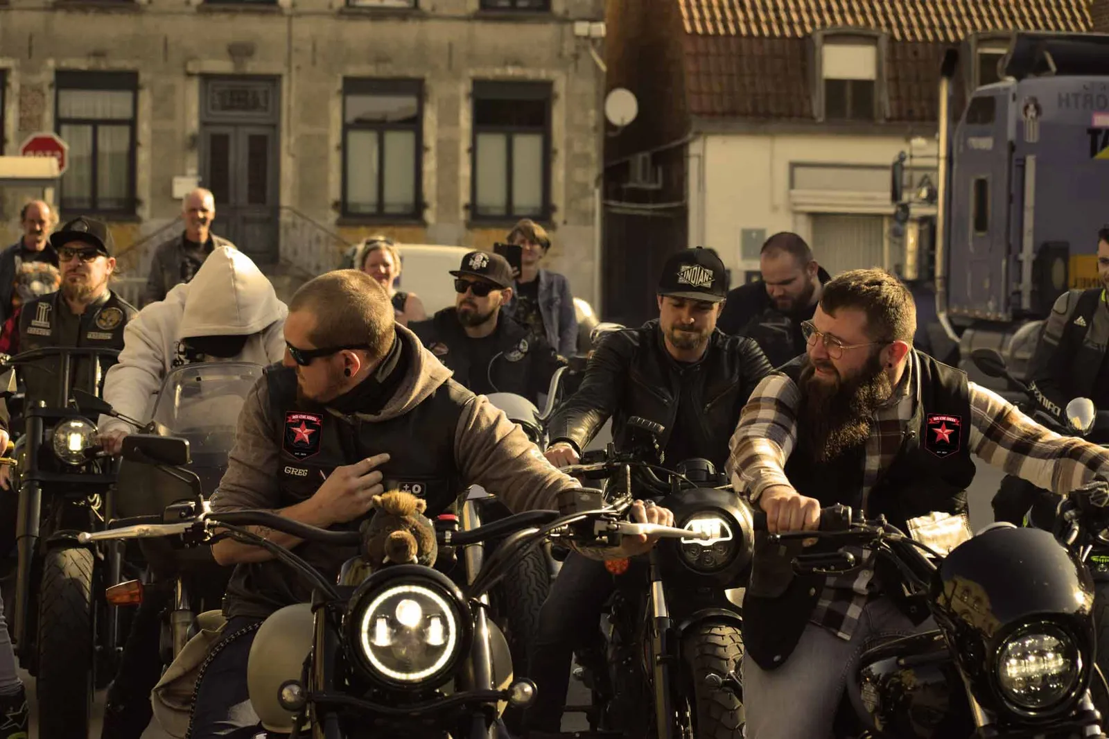 A group of motorcycle riders lined up for a ride, two of them wearing Red Star Riders patches on their vests